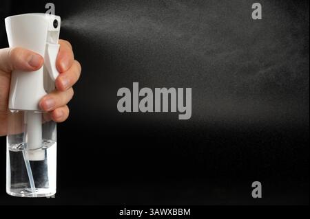 Spray white transparent liquid from bottle side view isolated on black background Stock Photo