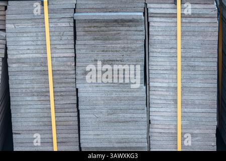 Densely stacked grey slabs of concrete secured with yellow straps. Construction materials in the vicinity Stock Photo
