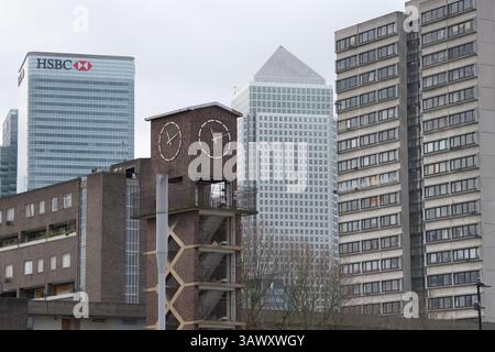 A contrasting London view of the municipal architecture with flats and clock at Chrisp Street Market in Poplar with skyscrapers in Canary Wharf Stock Photo