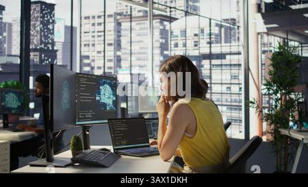 Hacker in office using laptop to steal company secrets, doing data breach, hiding from manager. Employee hired by competitor to spy, mining info from servers, closing notebook lid to hide, camera B Stock Photo