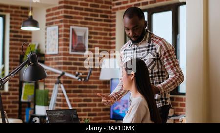 Diverse software developers team coding on a laptop in a cozy home office, working on a new program or app development. Specialists in IT promote programming language and remote tech work. Camera B. Stock Photo
