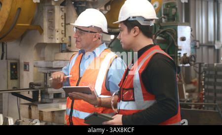 Engineer teaching apprentice to use metal sheet stamping machine Stock Photo