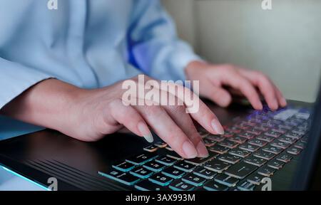 Close up Female hands using laptop computer, typing on keyboard while sitting on sofa, programmer, solopreneur, remote work, work from home, freelance Stock Photo
