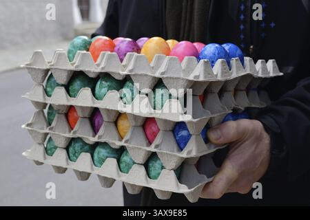 Person holding several stacks of coloured eggs for Easter Stock Photo