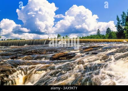 Dam waterfall at a river a sunny summer day in low angle view Stock Photo