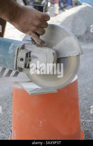 Skilled worker cuts tiles with angle grinder Stock Photo