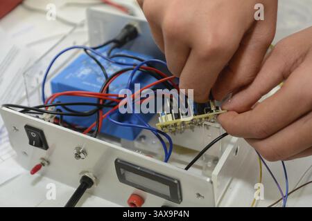 Skilled worker works on a power supply unit and connects wires Stock Photo