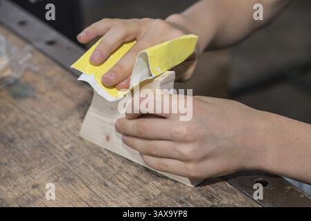 Sanding wood smooth with sandpaper - Woodworking by a carpenter with sandpaper Stock Photo