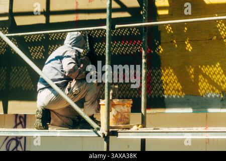 Construction worker on scaffolding working on building facade thermal insulation, selective focus Stock Photo