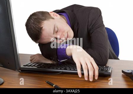 Young businessman falling asleep at his desk - Freisteller Young businessman falling asleep at his desk - isolated Stock Photo