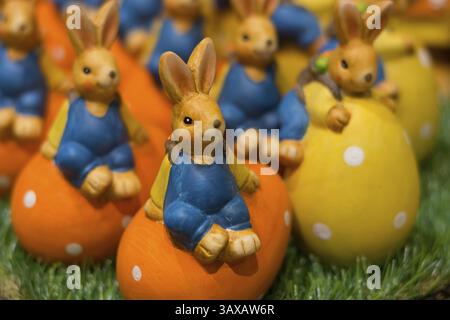 Numerous colourful ceramic Easter bunnies sit on colourful Easter eggs Stock Photo