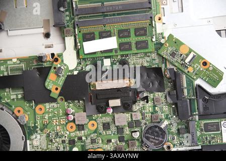 Opened laptop with motherboard and numerous soldered joints, battery, fan - Hardware Stock Photo