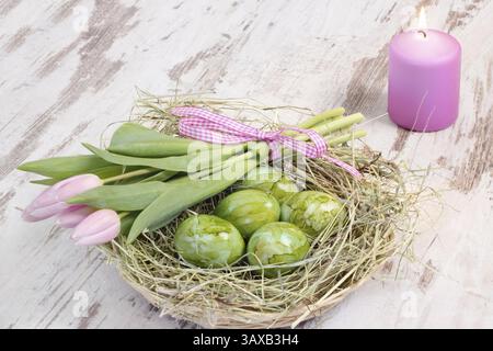 Candle and green Easter eggs with tulips in a hay nest Candle and green Easter eggs with tulips in a hay nest Stock Photo