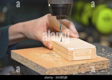Craftsman works with a stationary drill and drills a hole in softwood Stock Photo