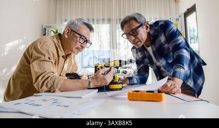 asian Senior engineer programming robot arm in automation and electronics technology lab Stock Photo