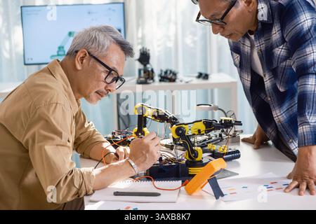 asian Senior engineer programming robot arm in automation and electronics technology lab Stock Photo