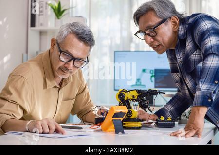 asian Senior engineer programming robot arm in automation and electronics technology lab Stock Photo