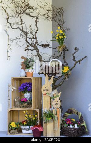 Creative upcycling Easter decoration in front of the house entrance with flowers and Easter bunny Stock Photo
