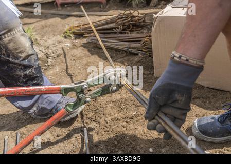 Construction worker working on building site with bolt cutters - close-up construction industry, pliers Stock Photo