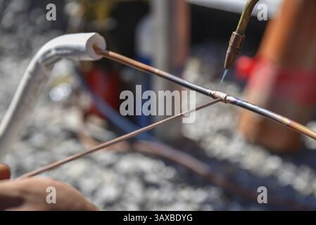 Tradesman working on site brazing copper pipe - Welding Stock Photo