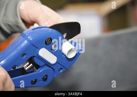 Tradesman plumber with single stroke pipe cutter - close-up tool pipe cutter, skilled worker Stock Photo