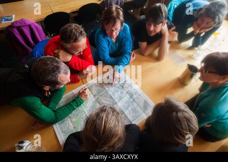 Group of backcountry skiers plan tour around map in Finsteraarhorn Hut Stock Photo