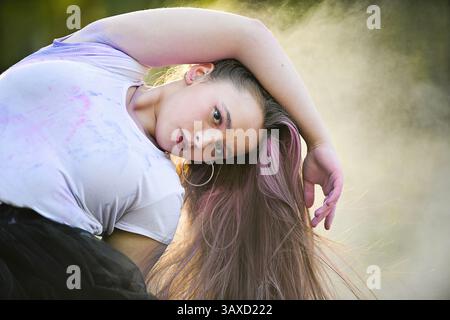 Woman in dramatic pose with long hair and pastel powder in air. Stock Photo