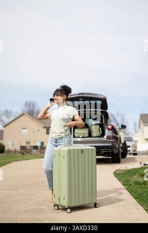 Woman walking with suitcase and talking on phone Stock Photo