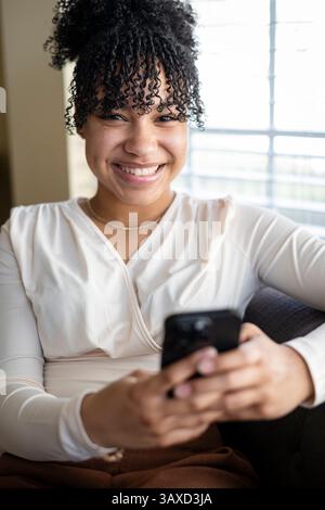 Woman holding phone and smiling at camera Stock Photo
