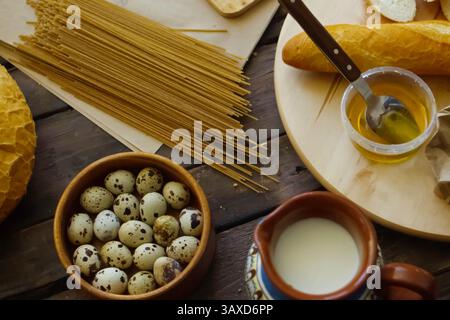 Kitchen still life - quail eggs, spaghetti, loaf of bread and butter on the table Stock Photo