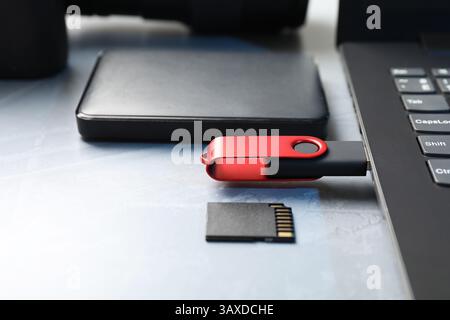 Flash drive connected to laptop, SD memory card and external hard disk on gray table, closeup Stock Photo