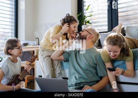 Father with three daughters trying to work from homeoffice. Stock Photo