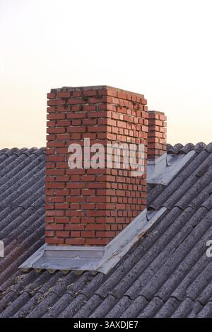 Two clinker brick chimneys on the roof - orange-red brick Stock Photo