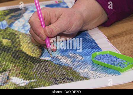 Person creates colourful picture with diamond painting - close-up Stock Photo