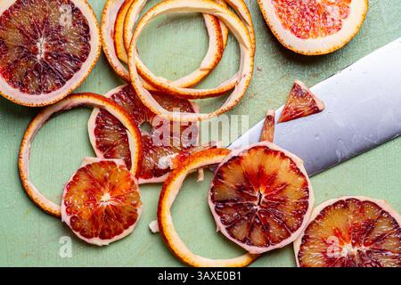 Blood oranges are cut with a knife on a green cutting board. High quality photo Stock Photo