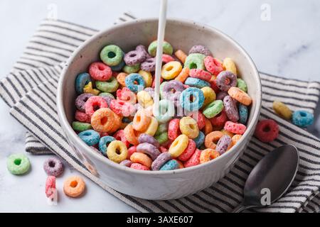 Colorful fruit rings cereal in bowl on a white marble background. Stock Photo