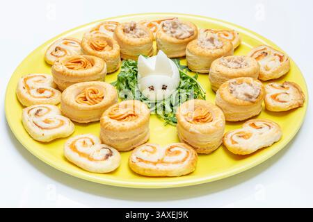 A hard-boiled egg in the shape of a bunny, surrounded by small puff pastry filled with salmon and tuna cream Stock Photo