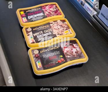 Kiel, Germany - 19. April 2025: Different flavors of Mövenpick ice cream tubs waiting on a grocery store checkout conveyor belt Stock Photo