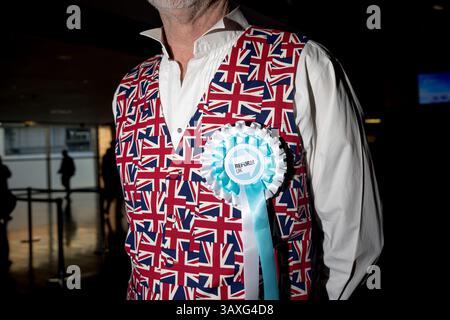 A supporter wearing a Union Jack waistcoat and a Reform UK rosette gathers for the Reform UK partyÕs local and mayoral election campaign launch rally at the Utilita Arena, Birmingham, England. Stock Photo