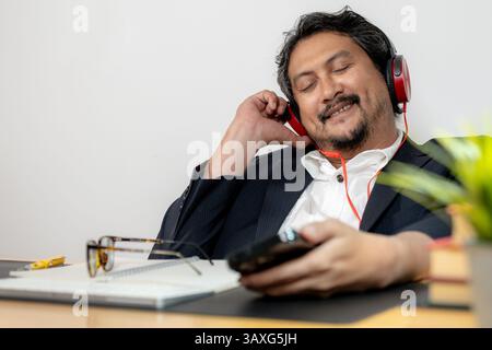 A businessman relaxing while listening to music with wireless headphones and a smartphone Stock Photo