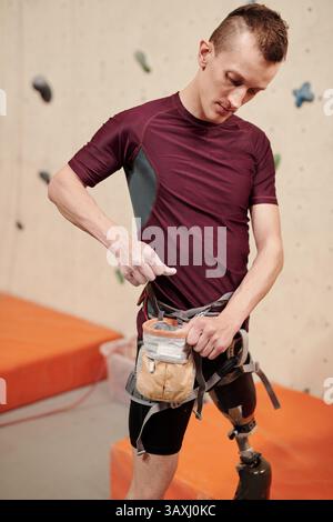Young disabled sportsman with leg prosthesis preparing for wall climbing Stock Photo