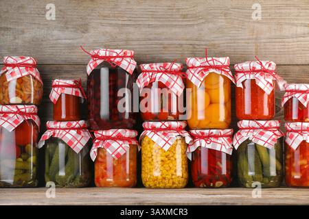Many jars with different pickled products on wooden table Stock Photo