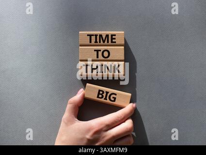 Time to think big symbol. Wooden blocks with words Time to think big. Beautiful grey background. Businessman hand. Business and Time to think big conc Stock Photo