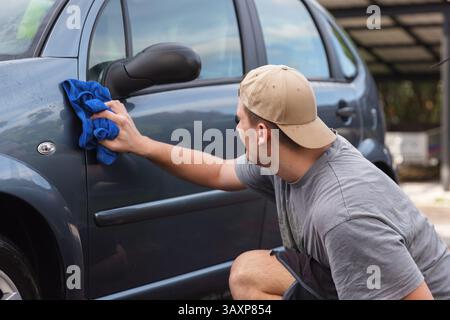 Young man cleaning his car outdoors at home Stock Photo