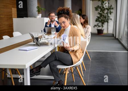 Professional businesswoman reviewing reports, using a tablet and laptop ...