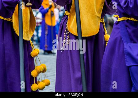 Good Friday procession En el Calvario in Cuenca. Processionists in purple robes with yellow details and rosaries. Plaza Mayor, Cuenca, Castile-La Mancha, Spain Stock Photo