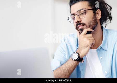 Closeup Portrait Of Focused Handsome Arab Guy In Eyeglasses Working On Laptop Stock Photo