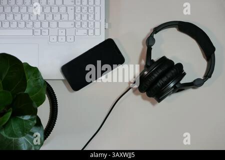 Flat lay on white background top view with copy space. Computer keyboard, headphones, house plant and smartphone. The concept of business, study or IT Stock Photo