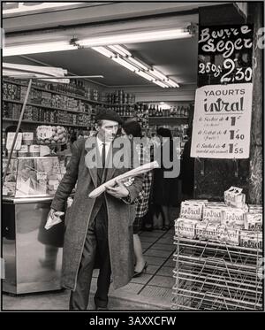 1965 Paris vintage retro Lifestyle fashion with typical French businessman in a hurry, wearing a beret leaving a delicatessen shop store with provisions including a typical French baguette Paris France: Willem Van de Poll 1965 Paris France Stock Photo