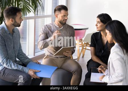 Multiethnic colleagues sit in office, engaged in focused discussion Stock Photo